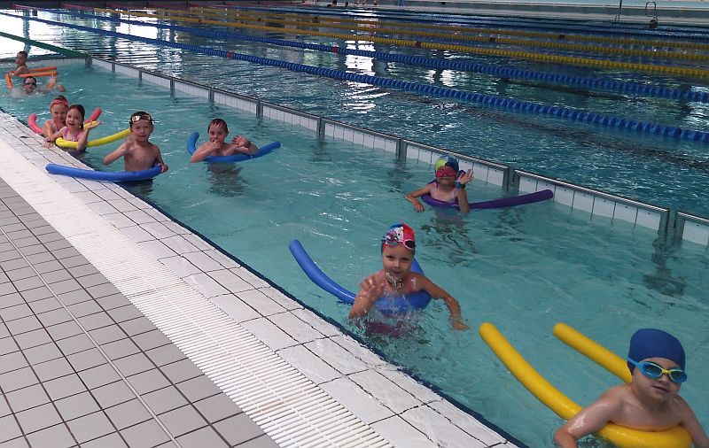 Grupa dzieci ucząca się pływać przy użyciu tzw. makaronów
